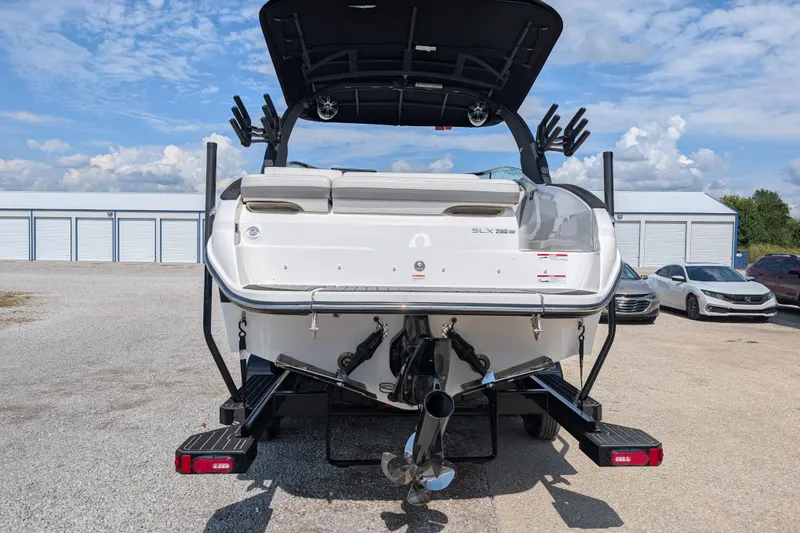 Slide: The Image of 2025 Sea Ray SLX 260 Surf boat rear view, parked outdoors under a blue sky. - 4