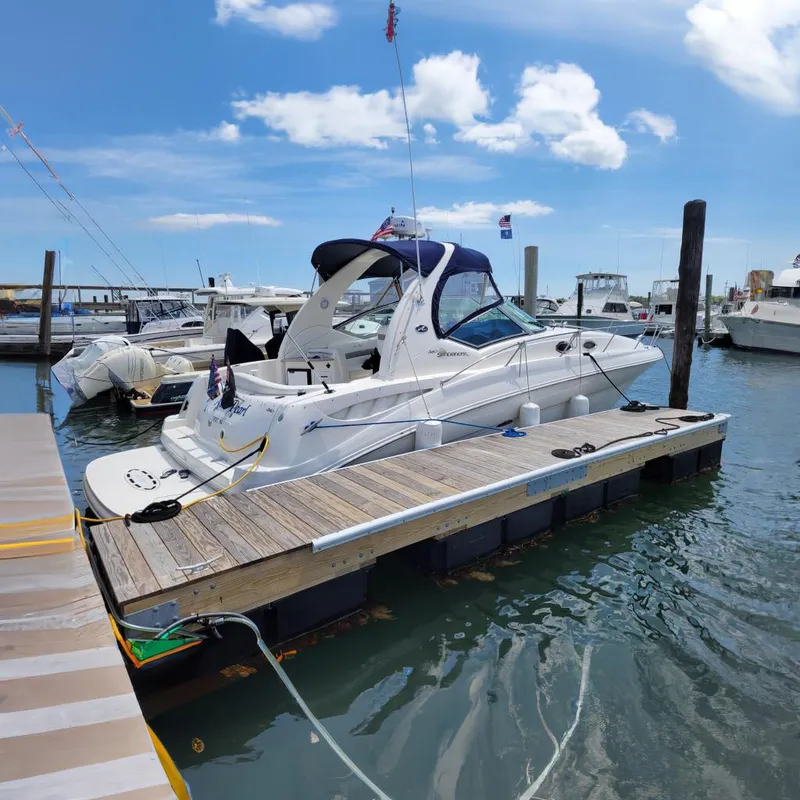 The Image of 2003 Sea Ray 320 Sundancer docked at a marina under a clear blue sky. - 0