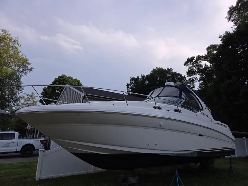 Slide: The Image of 2003 Sea Ray 320 Sundancer boat on land, surrounded by trees and a house. - 15