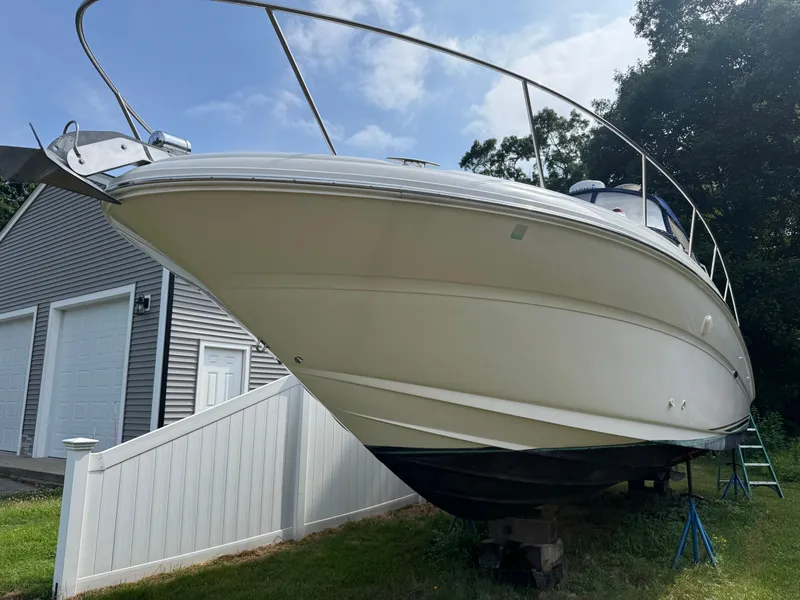 Slide: The Image of 2003 Sea Ray 320 Sundancer boat on stands near a garage, under a clear sky. - 17