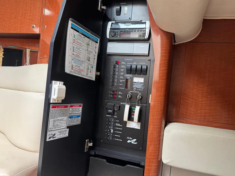 Slide: The Image of Electrical panel inside 2003 Sea Ray 320 Sundancer yacht, featuring control switches and safety instructions. - 29