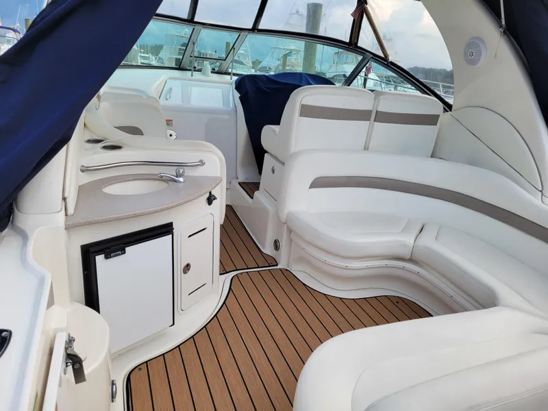 Slide: The Image of 2003 Sea Ray 320 Sundancer interior with white seating and compact kitchenette. - 5