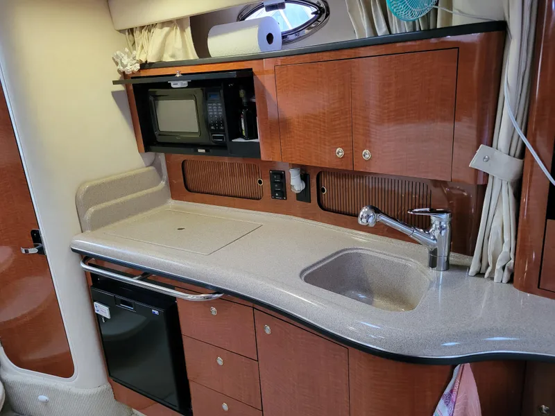 Slide: The Image of 2003 Sea Ray 320 Sundancer galley with sink, microwave, and storage cabinets. - 8
