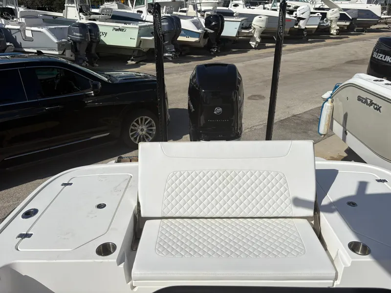 Slide: The Image of 2023 Caymas 28 HB boat with white seating and powerful outboard motor in a marina. - 7