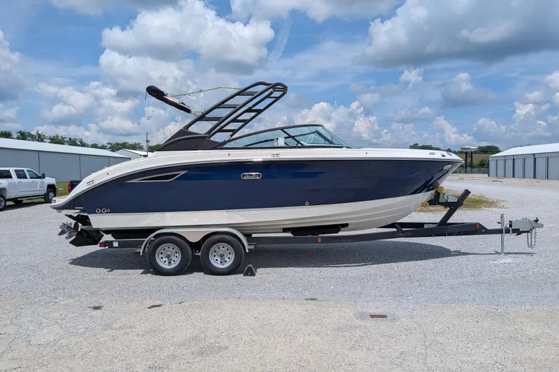 Slide: The Image of 2025 Sea Ray SDX 250 boat on trailer, parked outdoors under a cloudy sky. - 0