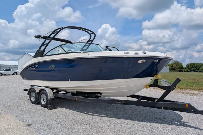 Slide: The Image of 2025 Sea Ray SDX 250 boat on trailer, parked outdoors under a cloudy sky. - 2