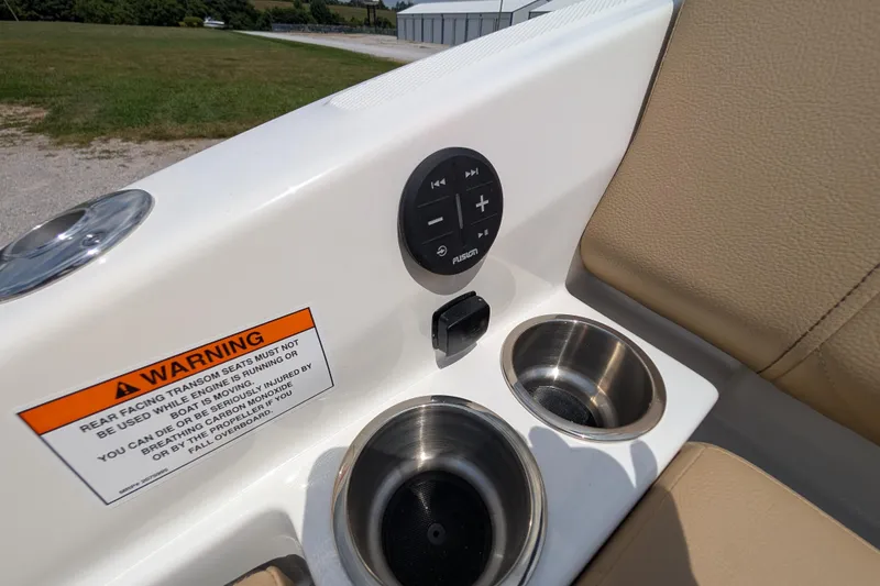 Slide: The Image of 2025 Sea Ray SDX 250 boat interior with warning label, audio controls, and cup holders. - 36