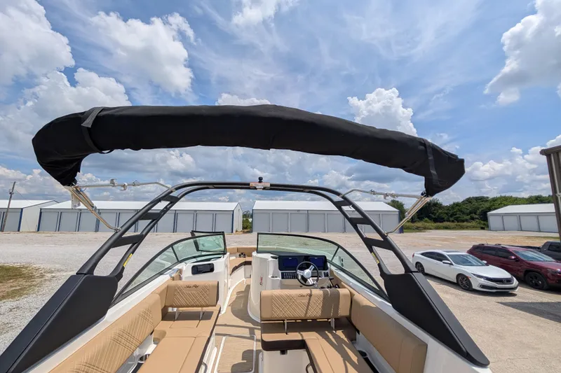 Slide: The Image of 2025 Sea Ray SDX 250 boat with canopy, parked outdoors under a partly cloudy sky. - 38