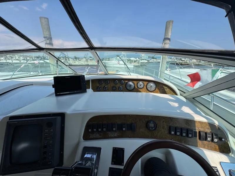 Slide: The Image of 1995 Sea Ray 370 Sundancer helm with navigation equipment and marina view. - 12