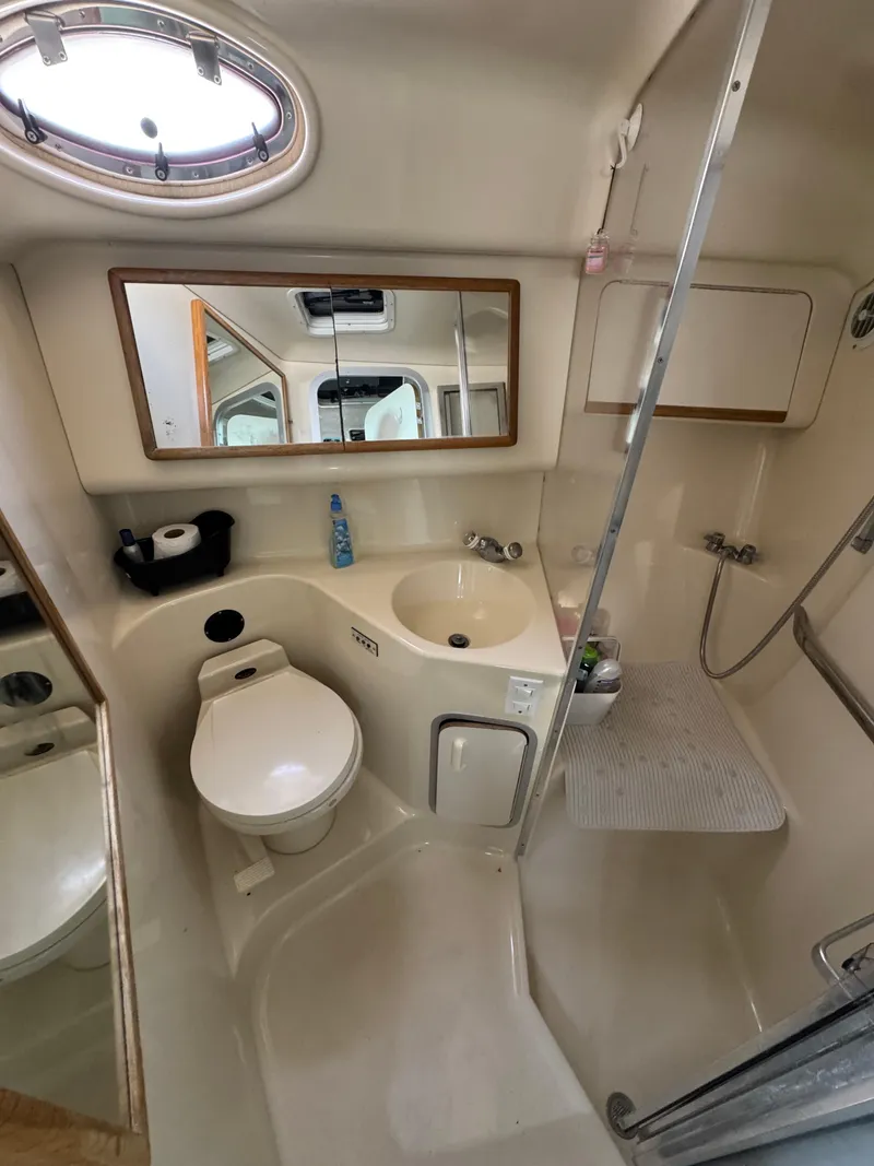 Slide: The Image of 1995 Sea Ray 370 Sundancer bathroom with toilet, sink, mirror, and shower. - 23