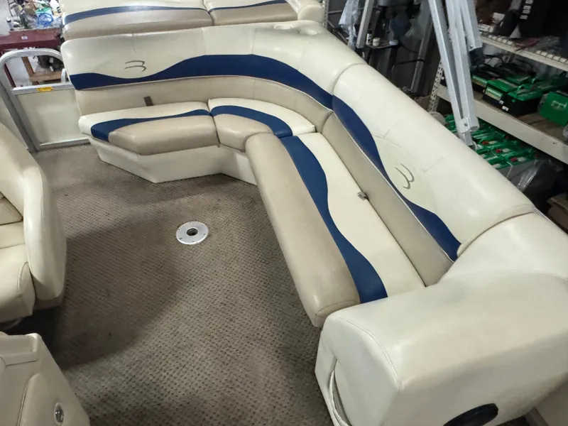Slide: The Image of 2003 Bennington 205L boat interior with beige and blue seating on carpeted floor. - 7
