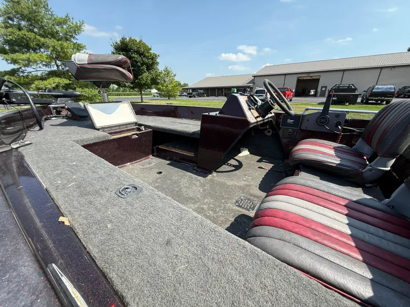 Slide: The Image of 1992 Ranger 320v boat interior with striped seats and steering wheel, parked outdoors. - 11