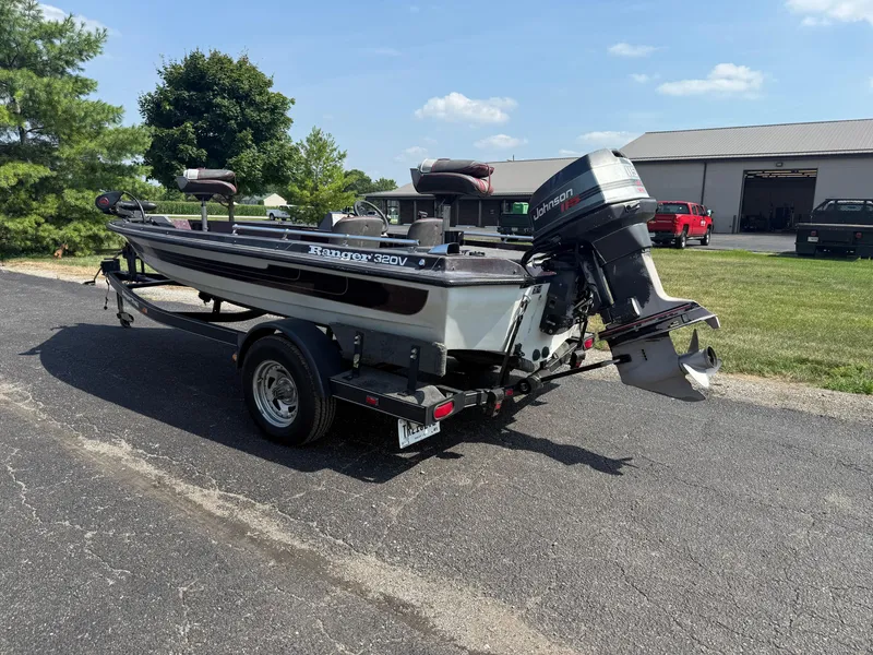 Slide: The Image of 1992 Ranger 320v boat with Johnson outboard motor on trailer, parked outdoors. - 4