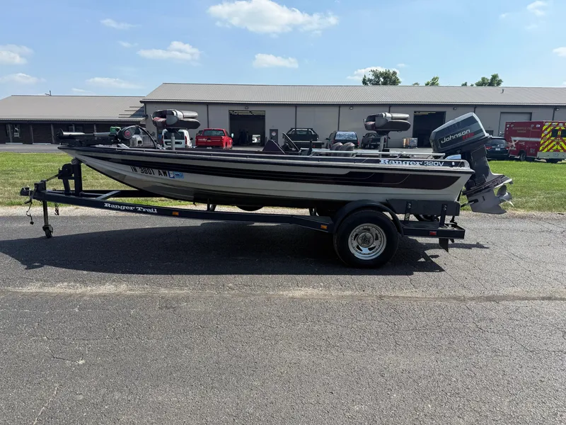 Slide: The Image of 1992 Ranger 320v boat on trailer, parked outdoors, with Johnson outboard motor. - 5