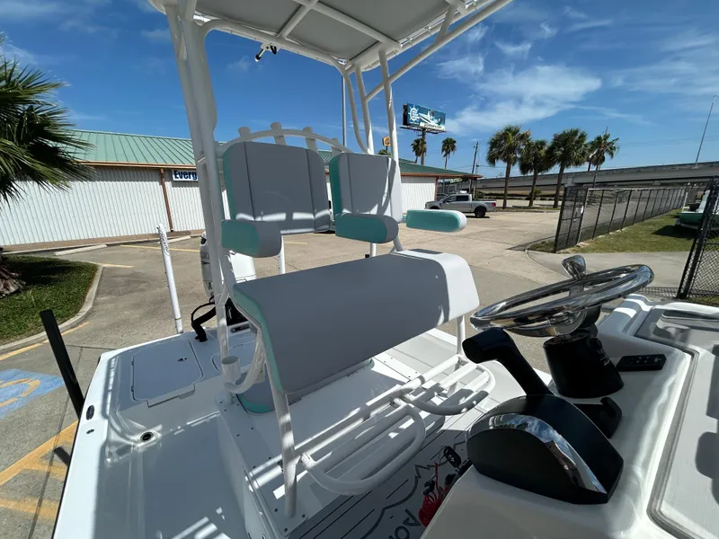 Slide: The Image of 2024 Shallow Sport 24 Modified V boat interior with steering wheel and seating, under clear blue sky. - 14