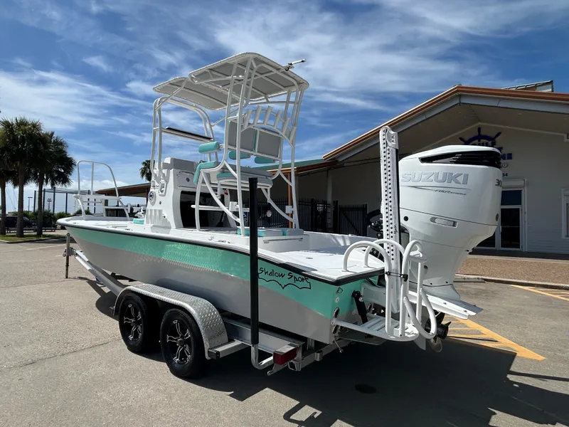 Slide: The Image of 2024 Shallow Sport 24 Modified V boat with Suzuki engine on trailer, outdoors. - 2
