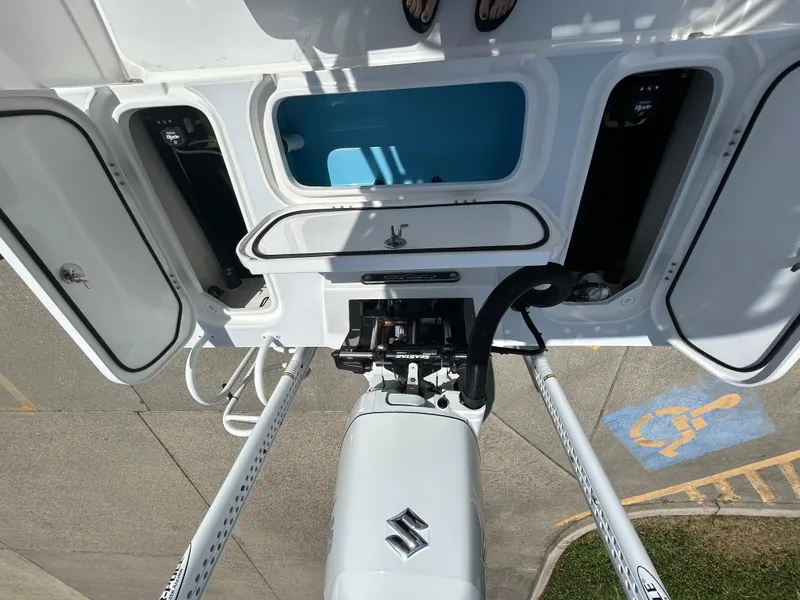 Slide: The Image of 2024 Shallow Sport 24 Modified V boat with open storage compartments and Suzuki engine. - 8