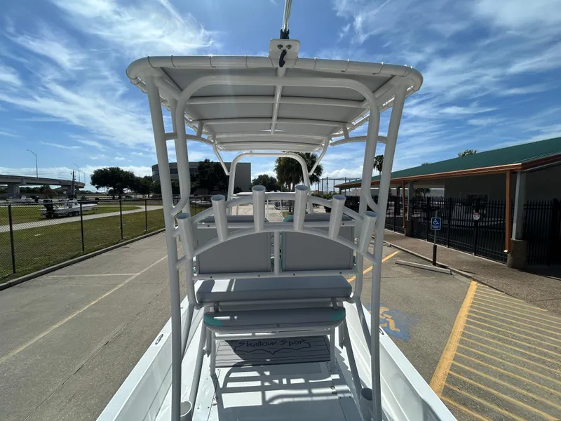 Slide: The Image of 2024 Shallow Sport 24 Modified V boat with T-top, parked under a clear blue sky. - 9