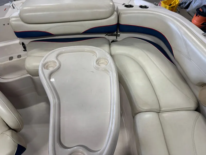Slide: The Image of 2015 Tahoe 215 Xi boat interior with white seating and table, featuring cup holders. - 10