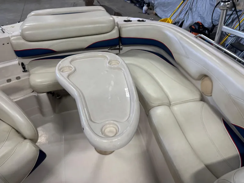 Slide: The Image of 2015 Tahoe 215 Xi boat interior with white seating and table, featuring cup holders. - 9