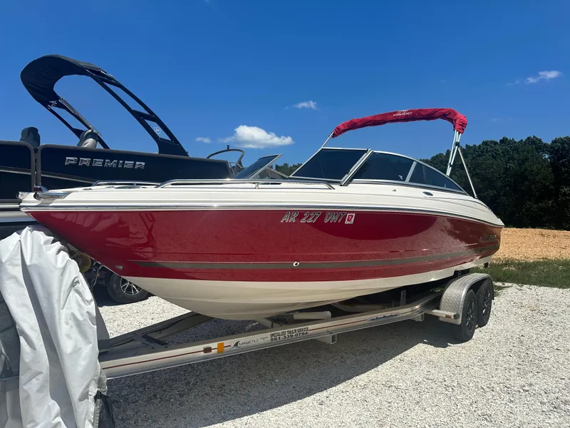 Slide: The Image of 2006 Monterey 194 FS boat with red hull on a trailer, parked outdoors. - 2