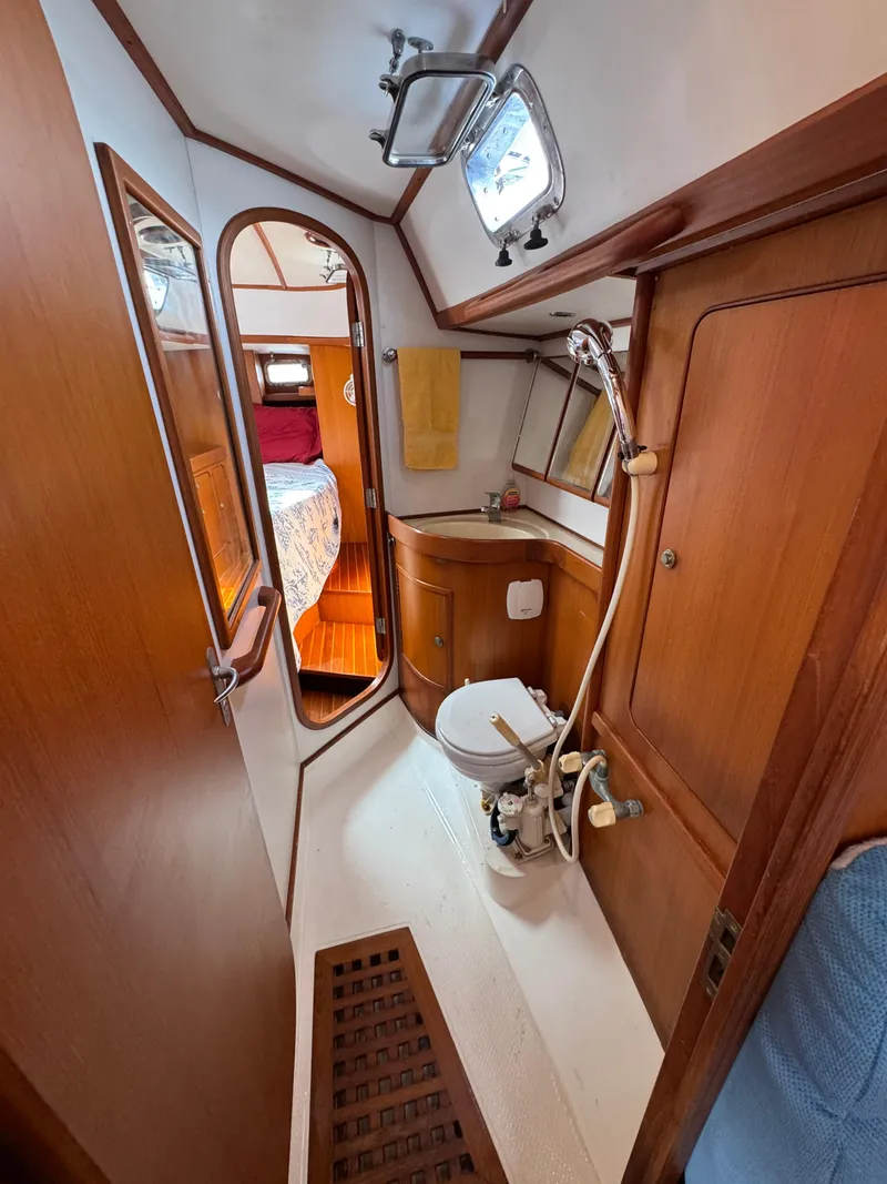 Slide: The Image of Hylas 46 yacht bathroom with wooden interior, shower, and adjacent bedroom view. - 12