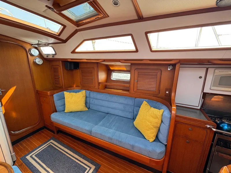 Slide: The Image of Interior of 1998 Hylas 46 yacht with blue sofa, yellow cushions, and wooden cabinetry. - 20
