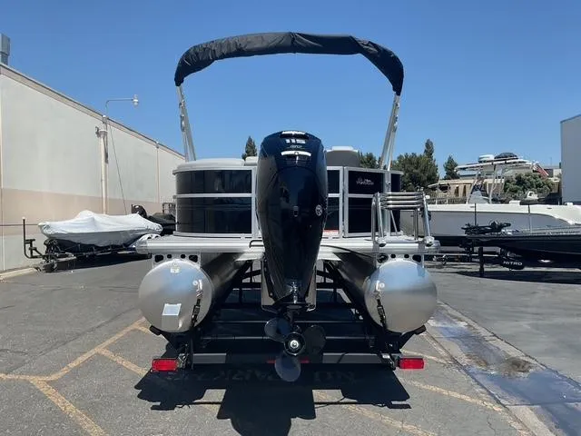 Slide: The Image of 2026 Sun Tracker Party Barge 20 DLX pontoon boat, rear view, parked outdoors. - 16