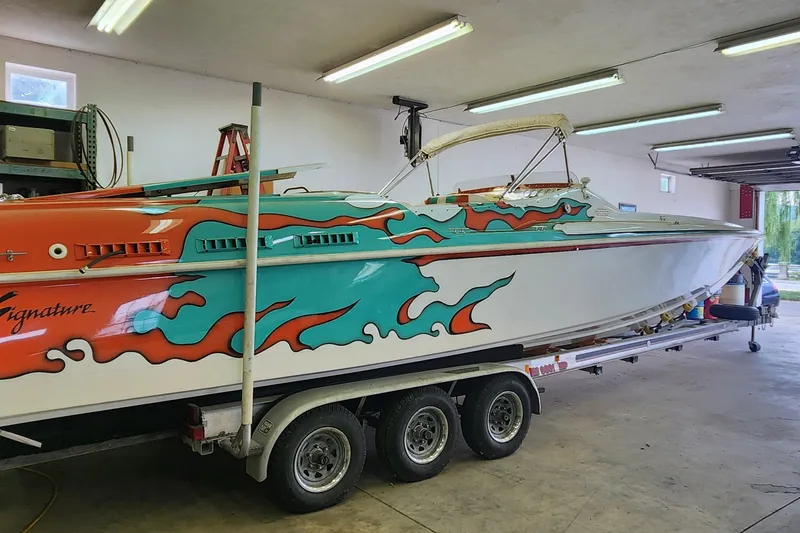 Slide: The Image of 1995 Cigarette 38 Signature Edition boat with vibrant flame design in a garage. - 0