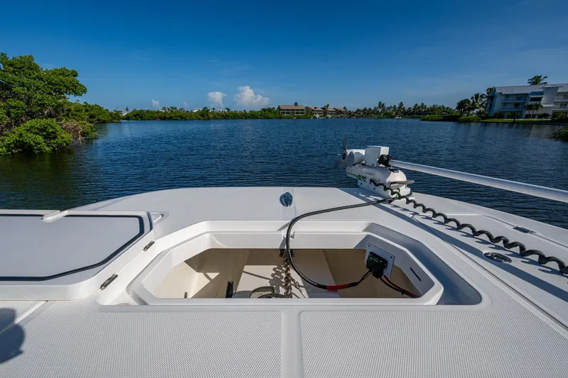 Slide: The Image of 2022 Invincible 33 Catamaran on serene lake, showcasing open hatch and lush surroundings. - 14