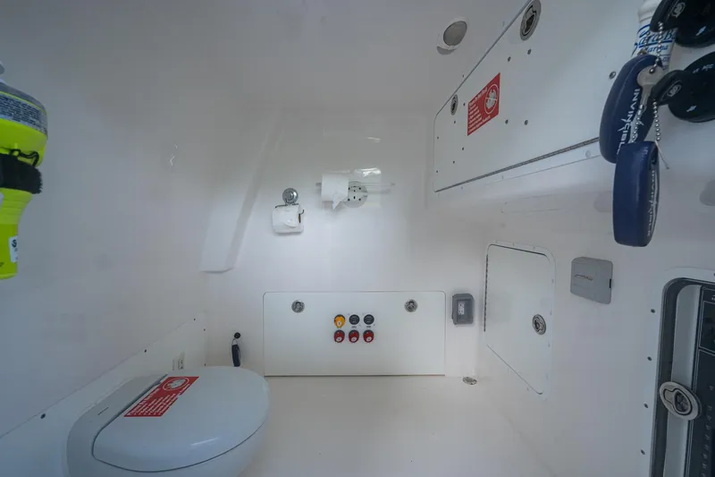 Slide: The Image of Interior of 2022 Invincible 33 Catamaran, featuring a compact marine toilet and storage compartments. - 32