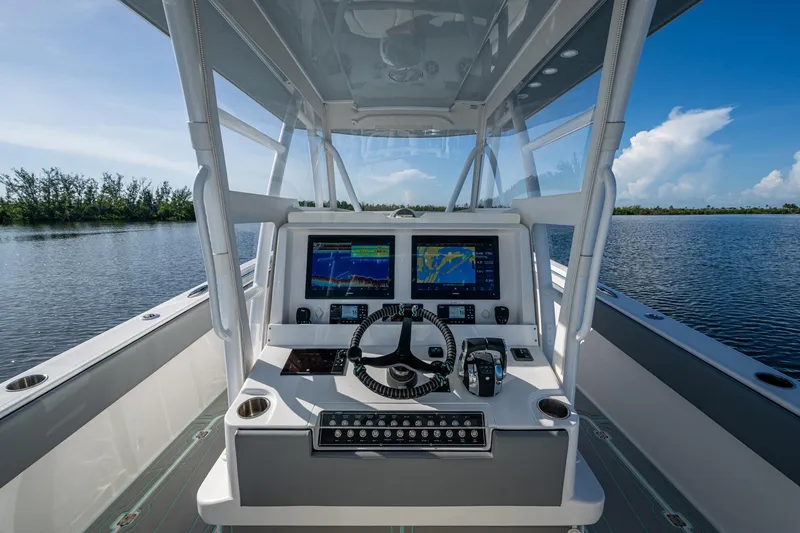 Slide: The Image of 2022 Invincible 33 Catamaran cockpit with advanced navigation system on a serene waterway. - 4
