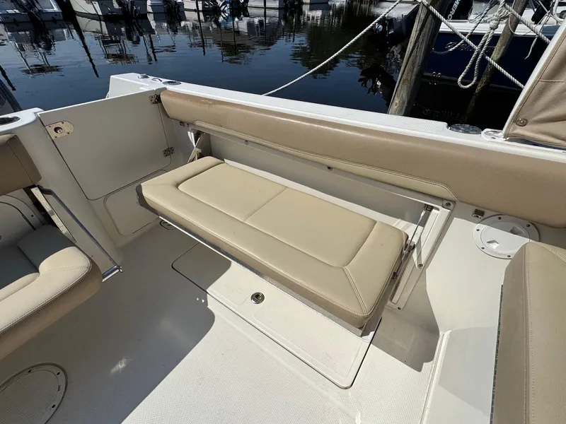 Slide: The Image of 2017 Sailfish 275 DC boat interior with beige seating and docked marina view. - 10