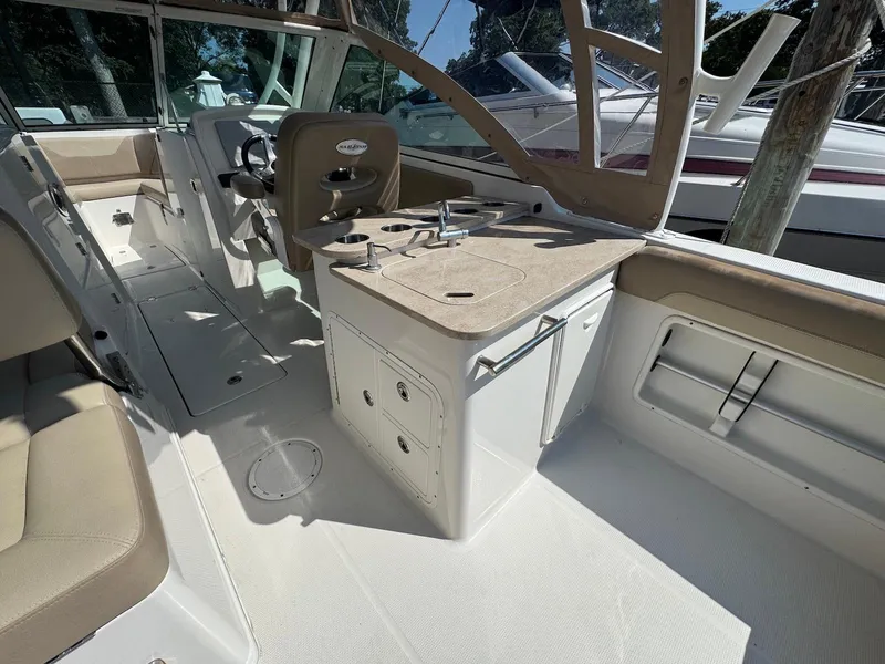 Slide: The Image of 2017 Sailfish 275 DC boat interior with seating, steering, and kitchenette area. - 13