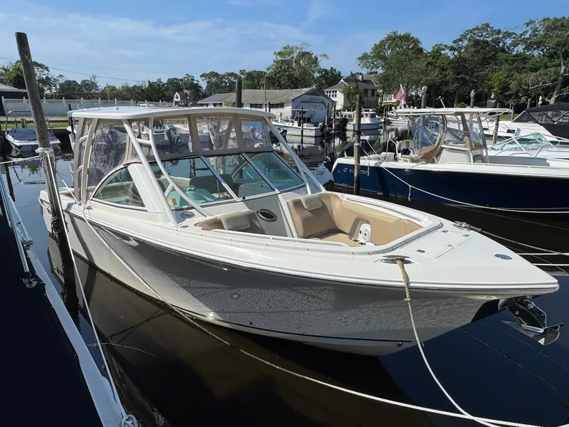 Slide: The Image of 2017 Sailfish 275 DC boat docked in a marina, surrounded by other boats. - 2