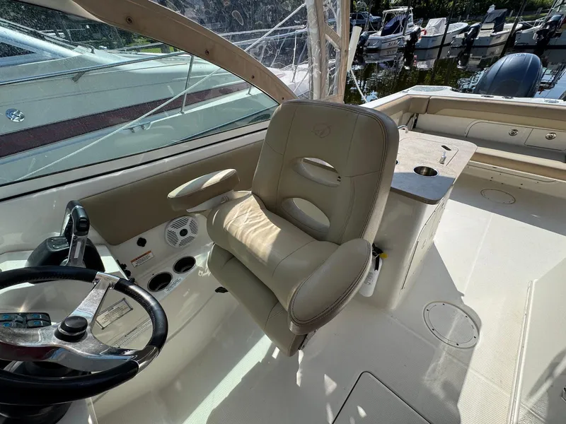 Slide: The Image of 2017 Sailfish 275 DC boat interior with steering wheel and beige captain's chair. - 20