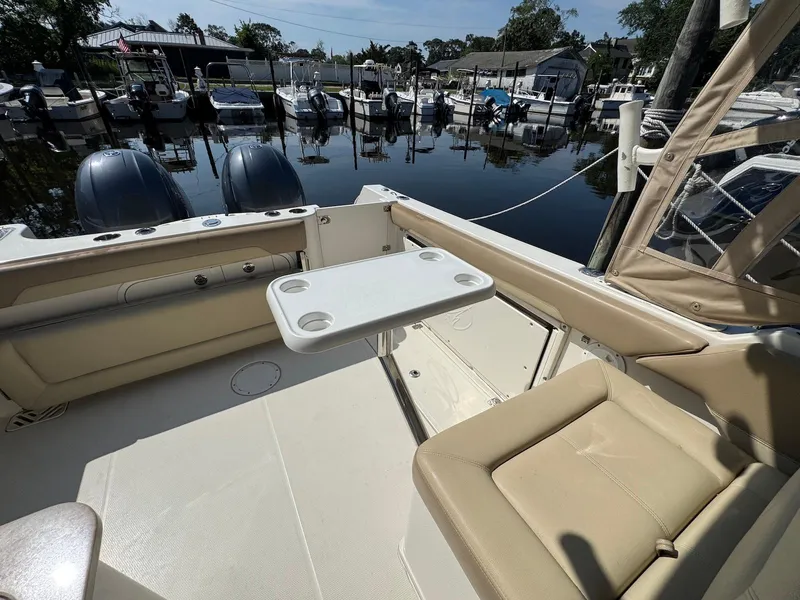 Slide: The Image of 2017 Sailfish 275 DC boat interior with seating and table, docked at a marina. - 23