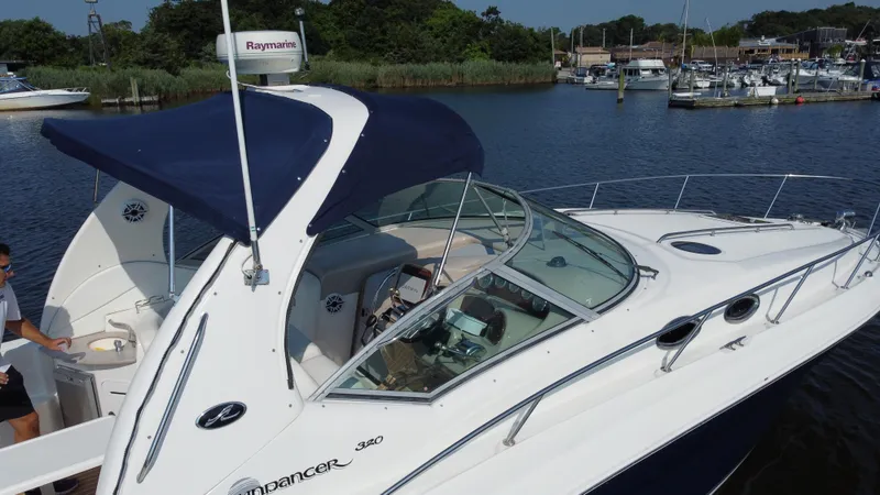 Slide: The Image of 2004 Sea Ray 320 Sundancer boat docked in a marina, featuring sleek design and blue canopy. - 11