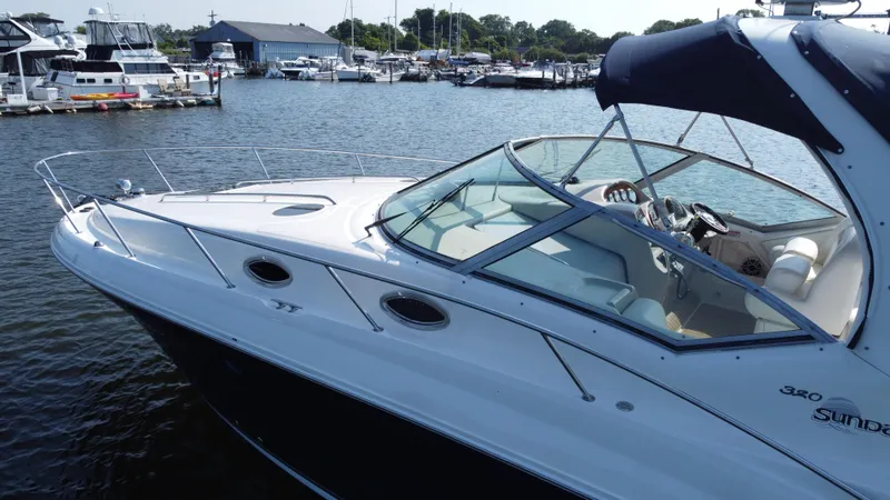 Slide: The Image of 2004 Sea Ray 320 Sundancer docked at marina, showcasing sleek design and spacious cockpit. - 12