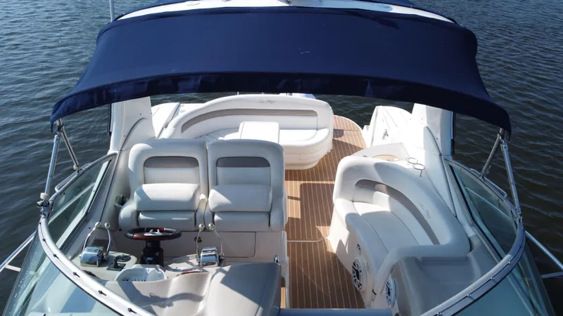 Slide: The Image of 2004 Sea Ray 320 Sundancer boat interior with seating and canopy on water. - 13