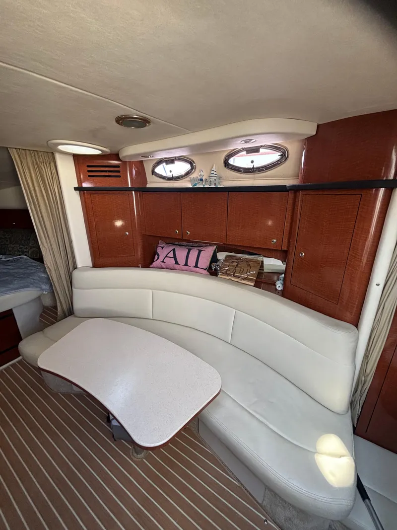 Slide: The Image of 2004 Sea Ray 320 Sundancer cabin with curved seating, wooden cabinets, and nautical decor. - 35
