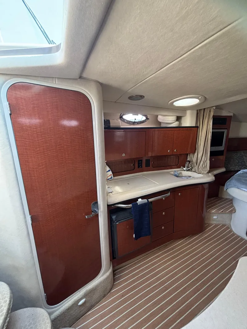 Slide: The Image of Interior of 2004 Sea Ray 320 Sundancer, featuring wood cabinetry and compact kitchen area. - 36