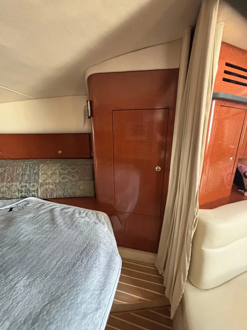 Slide: The Image of Interior of 2004 Sea Ray 320 Sundancer with wood paneling and cozy bedding. - 40