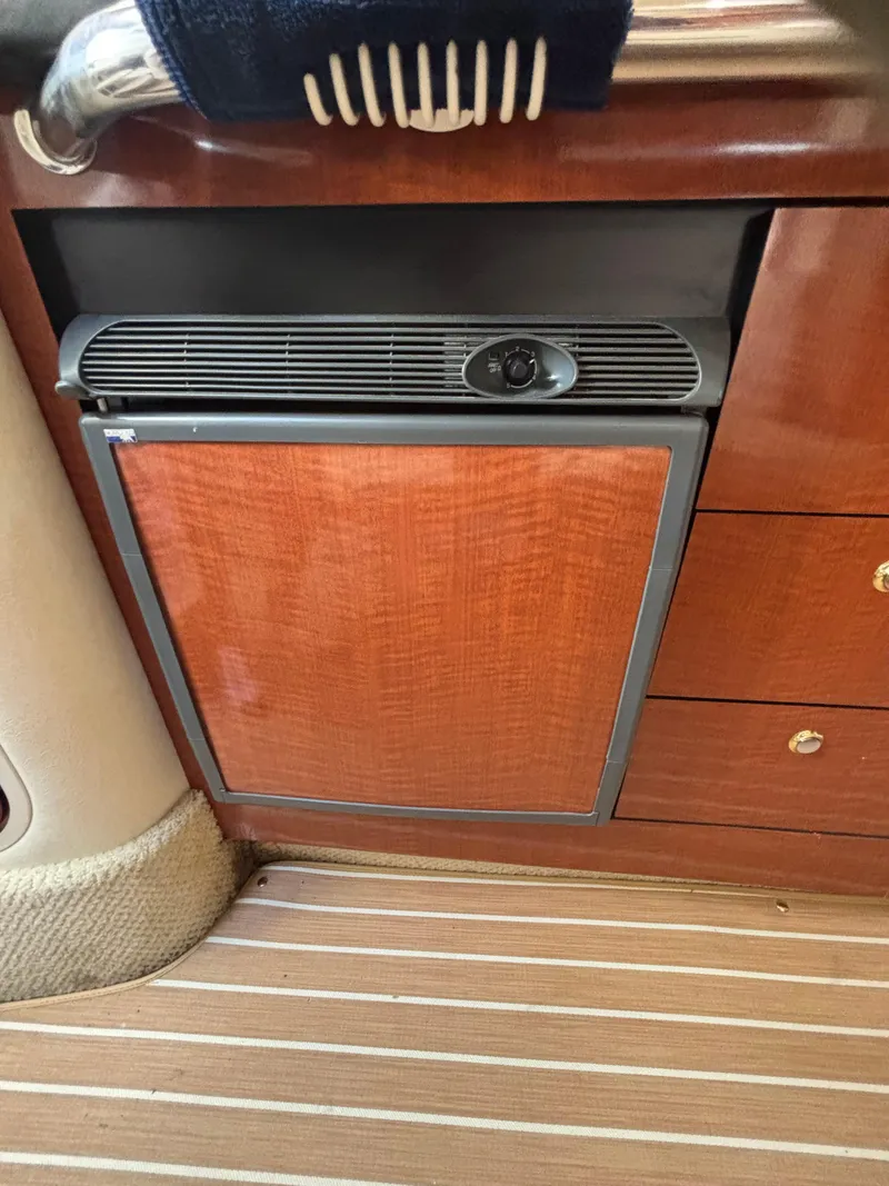 Slide: The Image of 2004 Sea Ray 320 Sundancer interior with wooden cabinetry and compact refrigerator. - 42
