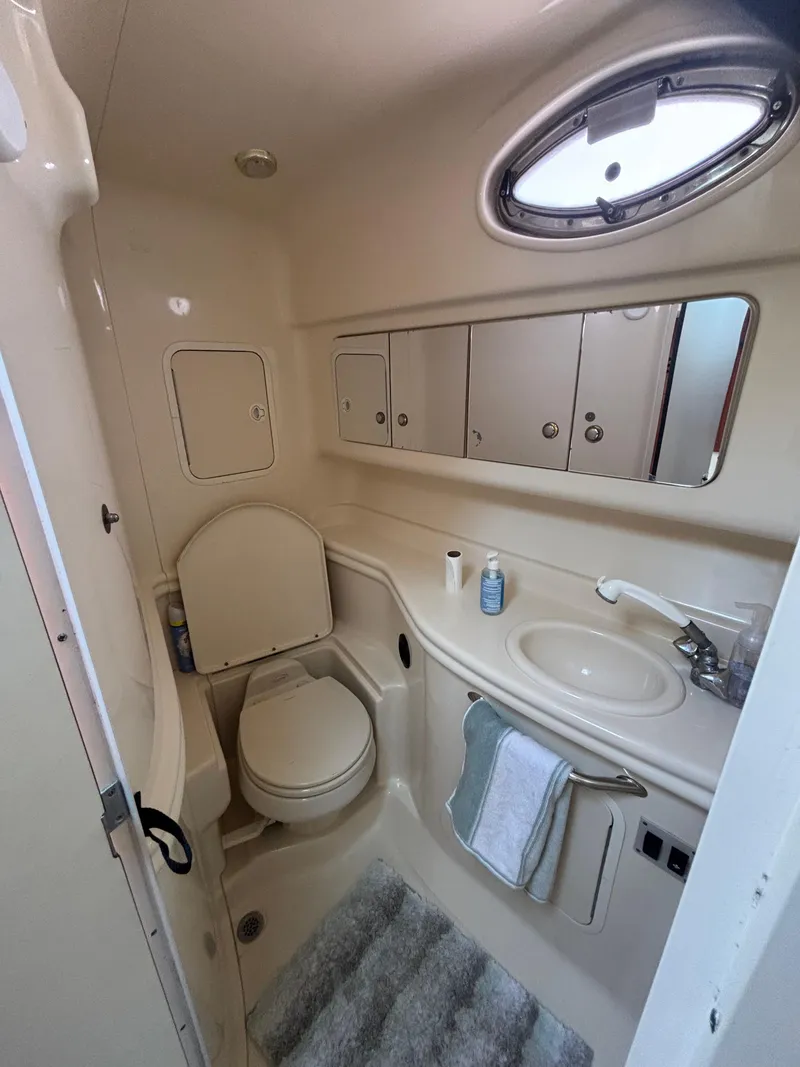 Slide: The Image of Compact bathroom in 2004 Sea Ray 320 Sundancer yacht, featuring sink, toilet, and storage cabinets. - 43