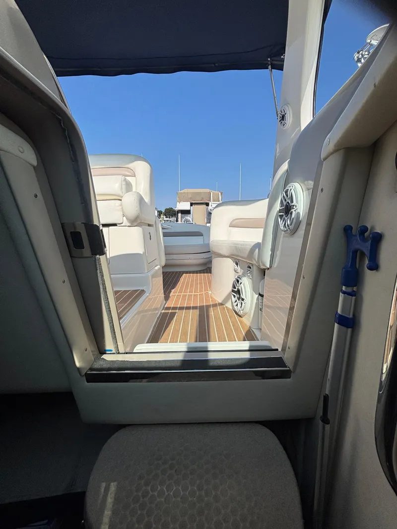 Slide: The Image of 2004 Sea Ray 320 Sundancer interior with seating and wooden flooring, under a blue canopy. - 46
