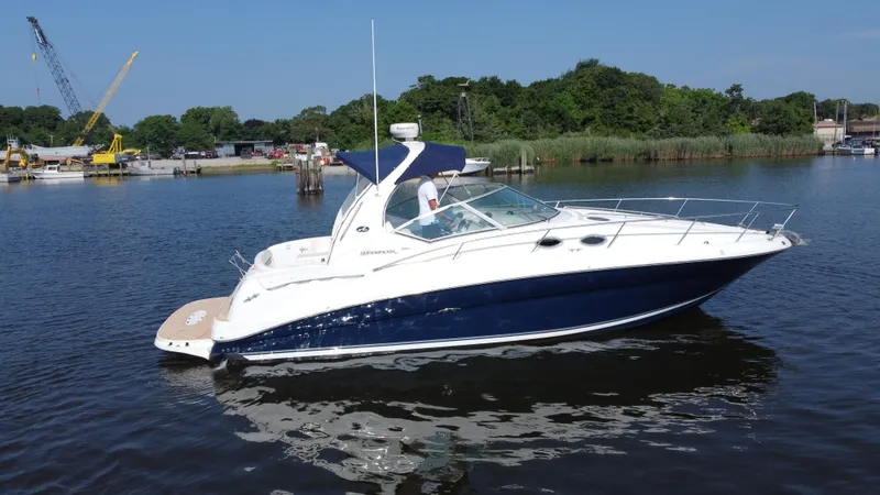 Slide: The Image of 2004 Sea Ray 320 Sundancer boat on calm water, with lush greenery in the background. - 6