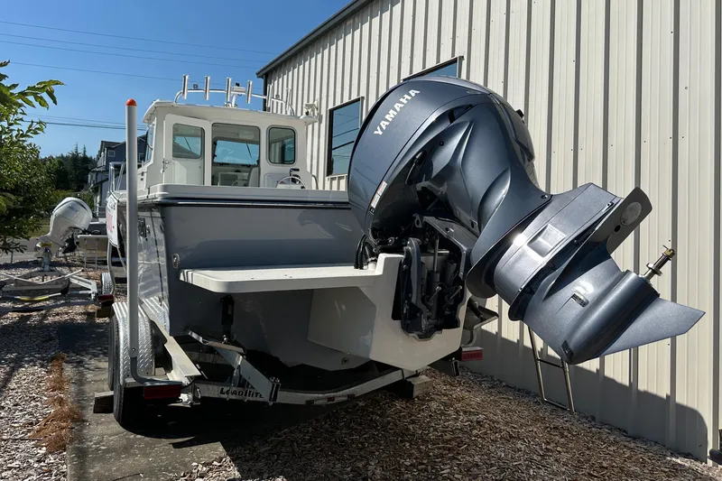 Slide: The Image of 2025 Parker 2420 Sport Cabin boat with Yamaha outboard motor, parked outdoors. - 5