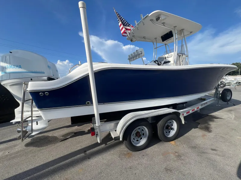 Slide: The Image of 2012 NauticStar 2500XS Offshore boat on trailer, blue hull, American flag, Yamaha engine. - 2