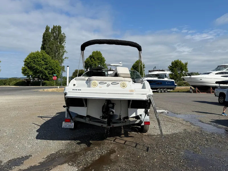 Slide: The Image of 2017 Crownline 205 SS boat parked on gravel near other boats and trees. - 2